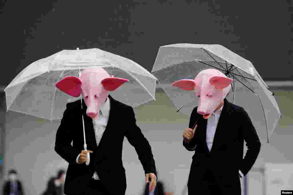 Youtubers wearing masks of pigs film a video at a shopping district in Tokyo, Japan.