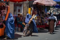 FILE - Burqa-clad women shop at a market in Kabul, Aghanistan, Aug. 23, 2021, following the Taliban's takeover of the country.