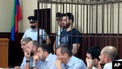 In this photo taken on June 16, 2019, Abdulmumin Gadzhiev, the religious affairs editor of the independent weekly Chernovik, stands in a cage in a court room in Makhachkala, the Caspian Sea province of Dagestan, Russia.