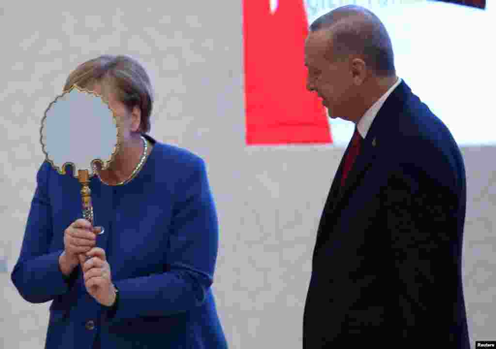 German Chancellor Angela Merkel receives a gift from Turkish President Tayyip Erdogan during the official opening ceremony of Turkish-German University's new campus in Istanbul, Turkey.