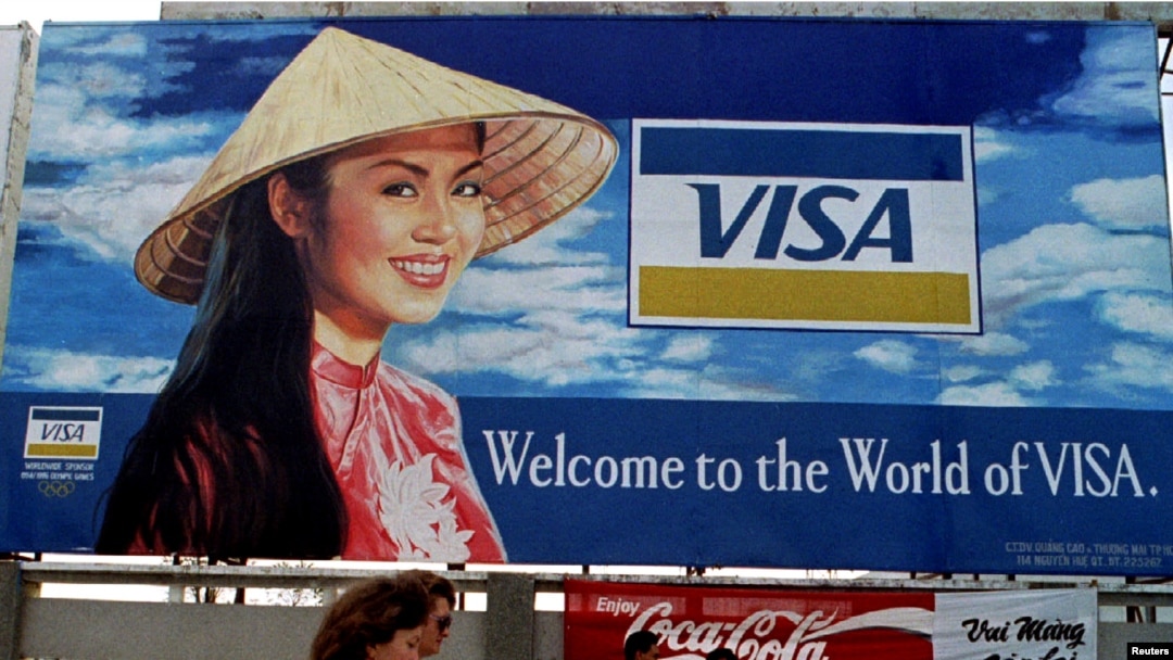 FILE - Tourists walk past advertisements of foreign companies near the airport of Ho Chi Minh City (formerly Saigon) March 8, 1994.