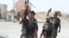 FILE - Shii'te volunteers carry their weapons during an intensive security deployment to fight against militants of the Islamic State, in Tuz Khurmatu, Iraq, Aug. 31, 2014. The Iraqi army and the Shi'ite Popular Mobilization Forces on Feb. 7, 2018, began cracking down on remaining IS fighters regrouping in Tuz Khurmatu.