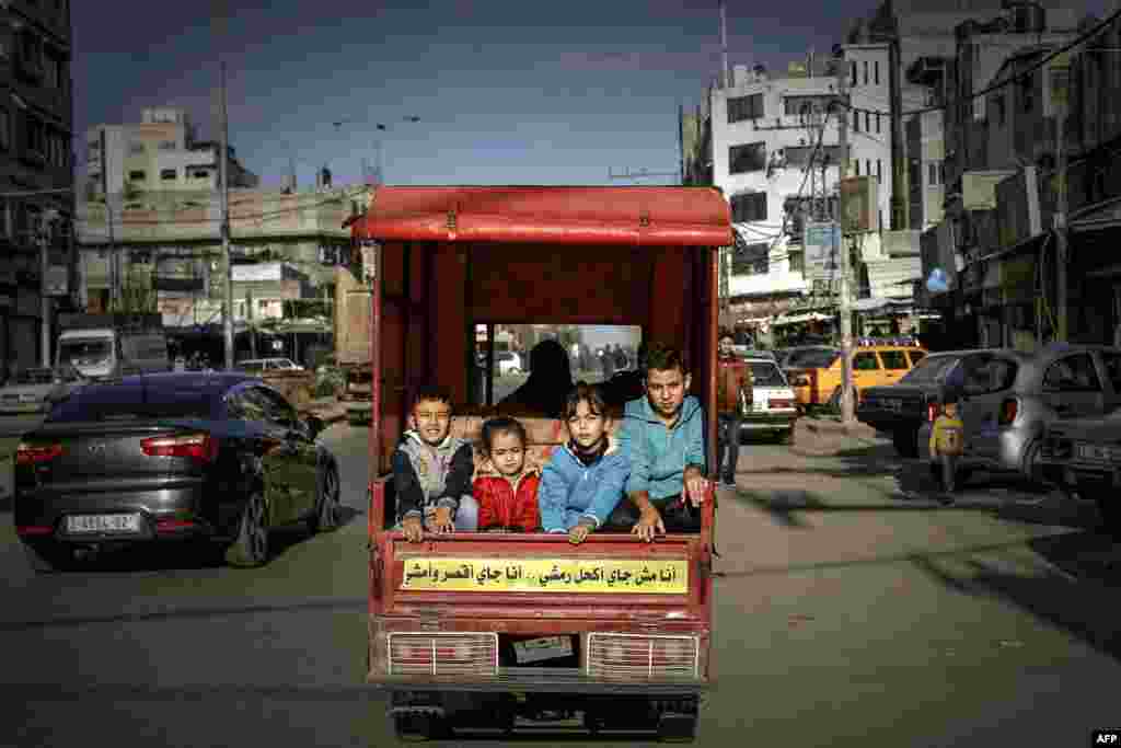 Palestinian children ride in the back of a tuktuk with their father on their way to a street market in Gaza City.