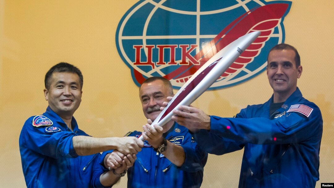 International Space Station (ISS) crew members, (L to R) Japanese astronaut Koichi Wakata, Russian cosmonaut Mikhail Tyurin and U.S. astronaut Rick Mastracchio, pose with the torch of the 2014 Sochi Winter Olympic Games, at the Baikonur cosmodrome, Nov. 6, 2013.