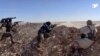 FILE - This frame grab from a video provided by the Syria Democratic Forces (SDF), shows fighters from the SDF opening fire on an Islamic State group's position, in Raqqa's eastern countryside, Syria, March 6, 2017.