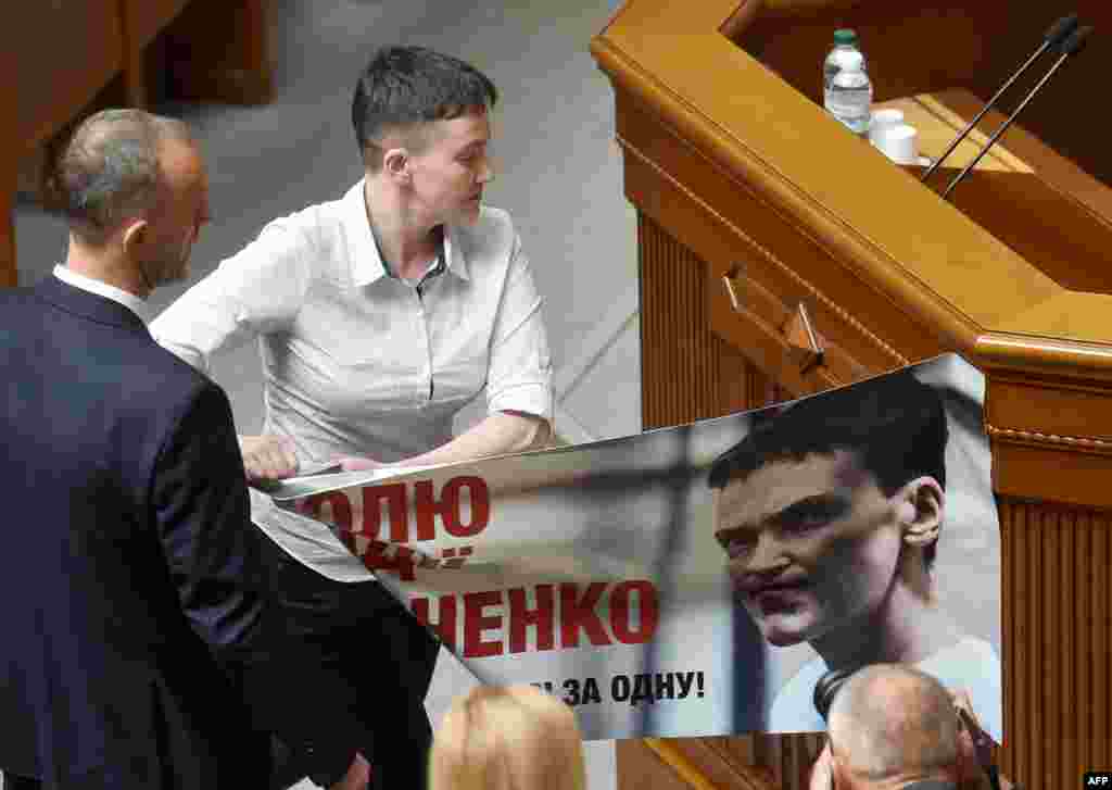 Ukrainian pilot Nadiya Savchenko removes a poster with her portrait, from a rostrum at the Ukrainian Parliament in Kyiv.