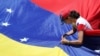 Una partidaria del líder opositor venezolano, Juan Guaidó, fija una bandera durante un mitin contra el gobierno del presidente venezolano Nicolás Maduro en Caracas. Abril 6, 2019.