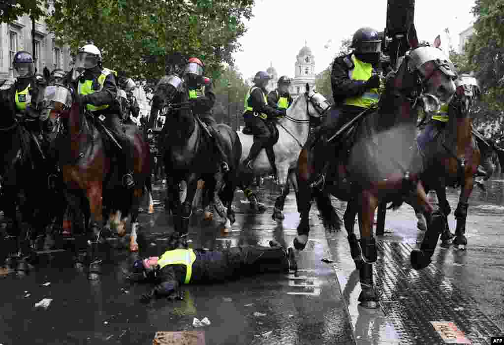 A mounted police officer is seen on the ground after being unseated from his horse, during a demonstration on Whitehall, near the entrance to Downing Street in central London, June 6, 2020, to show solidarity with the Black Lives Matter movement in the wake of the death of George Floyd who died in Minneapolis police custody. 