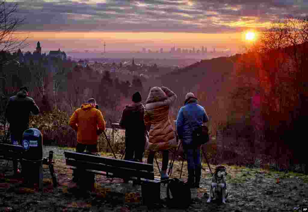 People take pictures of the sun rising next to the buildings of the banking district in Frankfurt, Germany, Dec. 28, 2019.