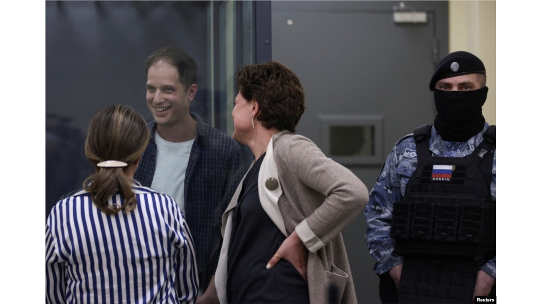 FILE - Wall Street Journal reporter Evan Gershkovich, who is in custody on espionage charges, speaks with his lawyers while standing behind a glass wall of an enclosure for defendants as he attends a court hearing in Moscow, Russia, April 23, 2024.