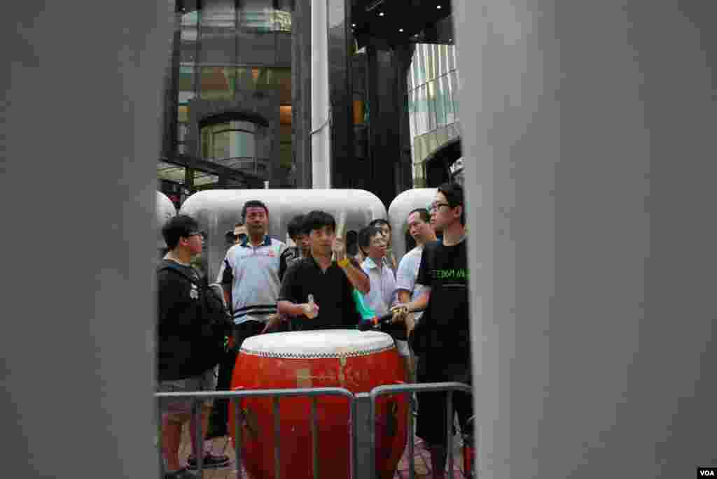示威人士在水馬陣隔著的示威區內擊鼓,喻意為李旺陽擊鼓鳴冤