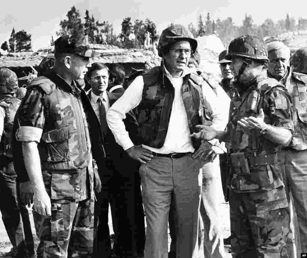 FILE - Then U.S. Vice President George Bush, center, wearing a flak jacket and steel helmet, is briefed at the site of a suicide truck bomb attack on the U.S. Marine barracks, near Beirut airport, Lebanon, Oct. 26, 1983.