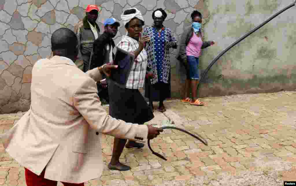 A government official uses a whip to attempt to disperse civilians who gathered to access relief food rations, amid concerns about the spread of coronavirus disease (COVID-19), in Nairobi, Kenya.