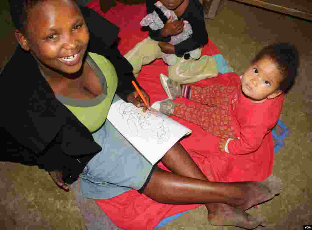 Lumka colors in with a few of Ikhaya Loxolo’s younger residents (VOA/ D. Taylor)