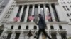 FILE - People pass the New York Stock Exchange in New York, June 24, 2016. The topic of Britain's vote to leave the European Union after a bitterly divisive referendum campaign has already made its way into the U.S. presidential race.