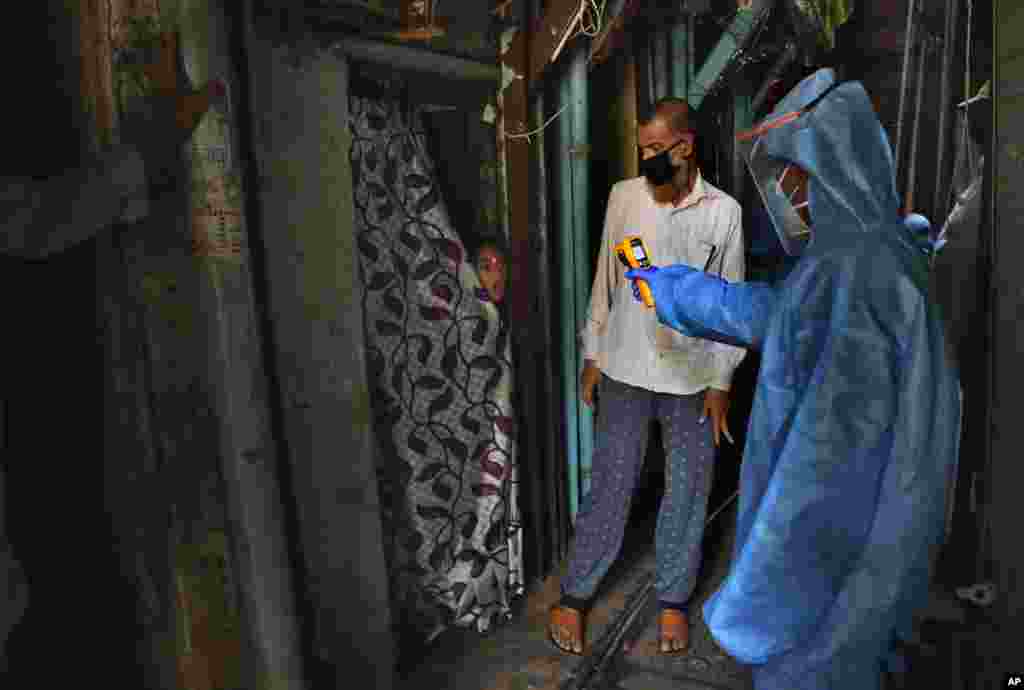 A doctor checks the temperature of a girl in Dharavi, one of Asia's largest slums, during lockdown to prevent the spread of the new coronavirus in Mumbai, India.