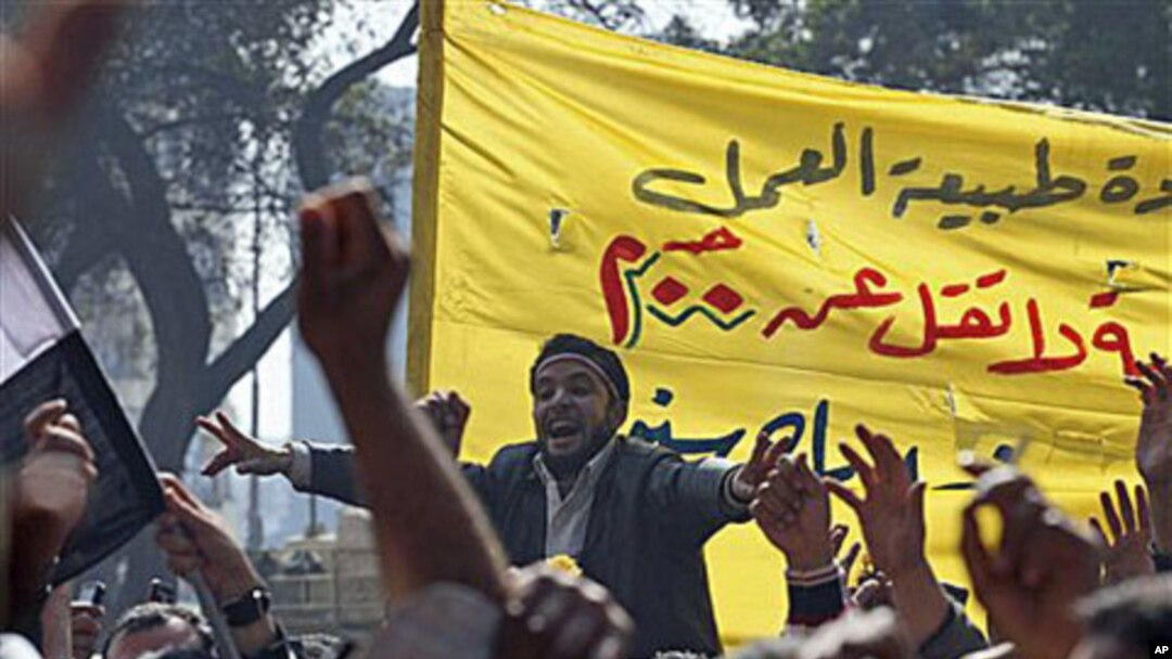Public transportation workers protest in demand of salary raises in front of the national TV building, right, in Cairo, Egypt, February 14, 2011