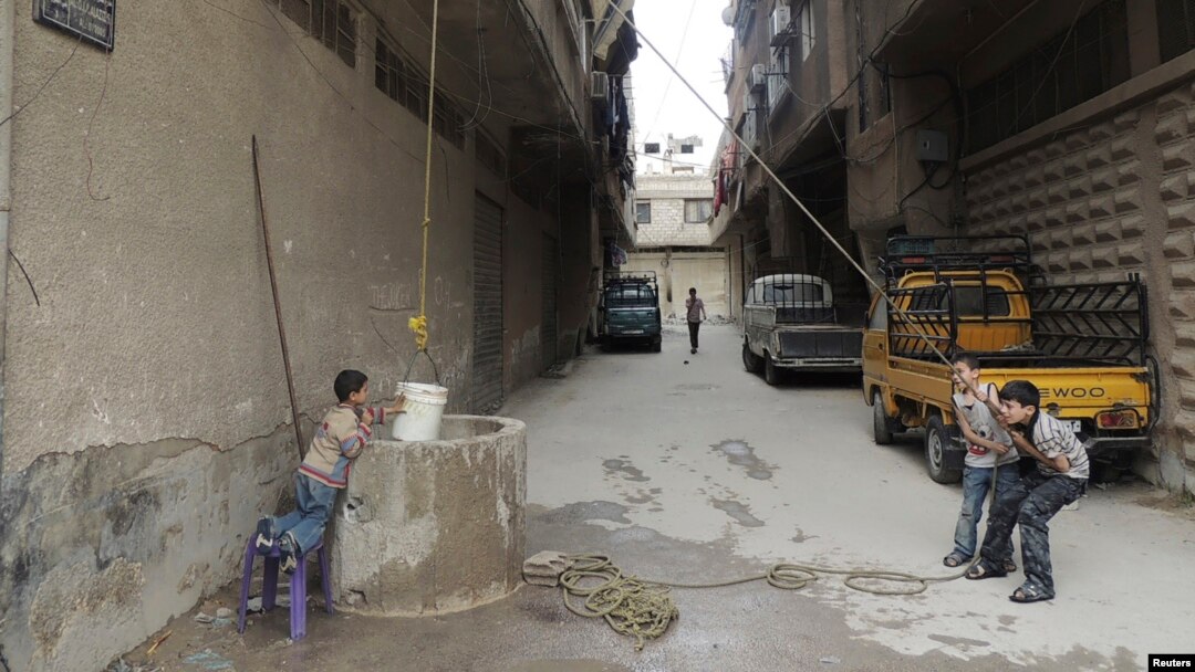 Boys use a bucket to extract water from a well in Arbeen, in the eastern Damascus suburb of Ghouta. Facing water shortages, residents started drilling wells to extract water to be used for drinking and domestic use, May 6, 2014. 
