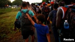 Xabiel, un migrante venezolano de 9 años, camina con su hermano Yilber Gabriel mientras se unen a la caravana que se dirige a la frontera sur de EE. UU., cerca de Villa Comaltitlán, México, el 20 de noviembre de 2021.