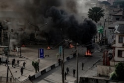 Armed men are seen near burning tires on a street in Lagos, Nigeria Oct. 21, 2020, in this image obtained from social media. (Credit: UnEarthical)