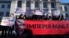 Protesters hold posters reading: "We will never surrender!" "Donbass is Ukraine!" and a banner "The empire must die" in front of Russian Embassy in Kyiv, Ukraine, Feb. 22, 2022. (AP/Efrem Lukatsky)