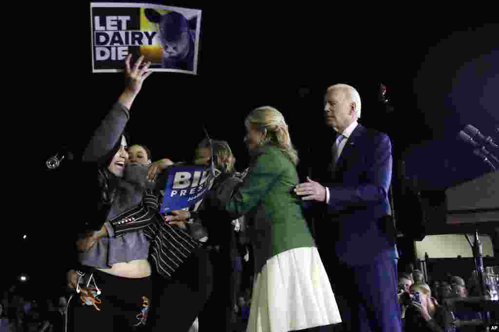 A protester, left, is held back by Biden's adviser Symone Sanders, wearing stripes, and his wife Jill Biden, second from right, as Democratic presidential candidate former Vice President Joe Biden stands, at right, during a primary election night rally in Los Angeles, California, March 3, 2020.