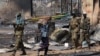 A Sudanese man carries a bed past South Sudan People's Liberation Army (SPLA) national army soldiers patrolling the town of Bentiu in January. Fresh fighting broke out in Bentiu this week.