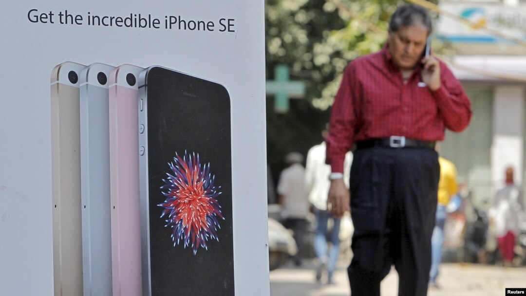 A man speaks on his mobile phone as he walks past an Apple iPhone SE advertisement billboard in a street in New Delhi, India, April 25, 2016.