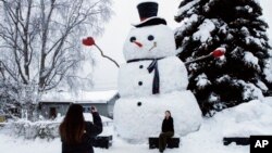 ARCHIVO - Isil Mico toma una foto de su cuñada Oznur Mico delante de Snowzilla, un muñeco de nieve de más de 6 metros de altura, en Anchorage, Alaska, el 10 de enero de 2024. 