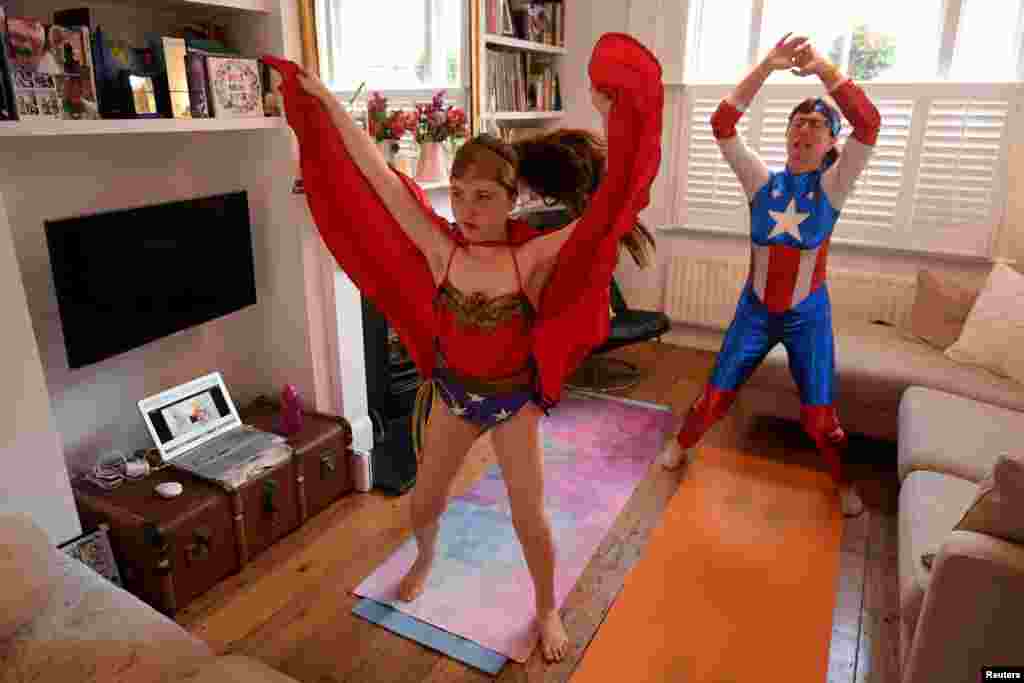 Dressed as superheroes, Jo Proudlove and daughter Eve, 9, follow the daily online "PE with Joe" Joe Wickes' exercise class on "Fancy dress Friday," at home in London, as the spread of the coronavirus disease (COVID-19) continues.