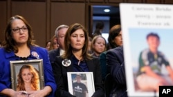 FILE - People hold photos of their children during a Senate Judiciary Committee hearing on online safety for children Feb. 14, 2023, in Washington. Studies have found women experience more online abuse, and harassment is driving girls to quit social media platforms.