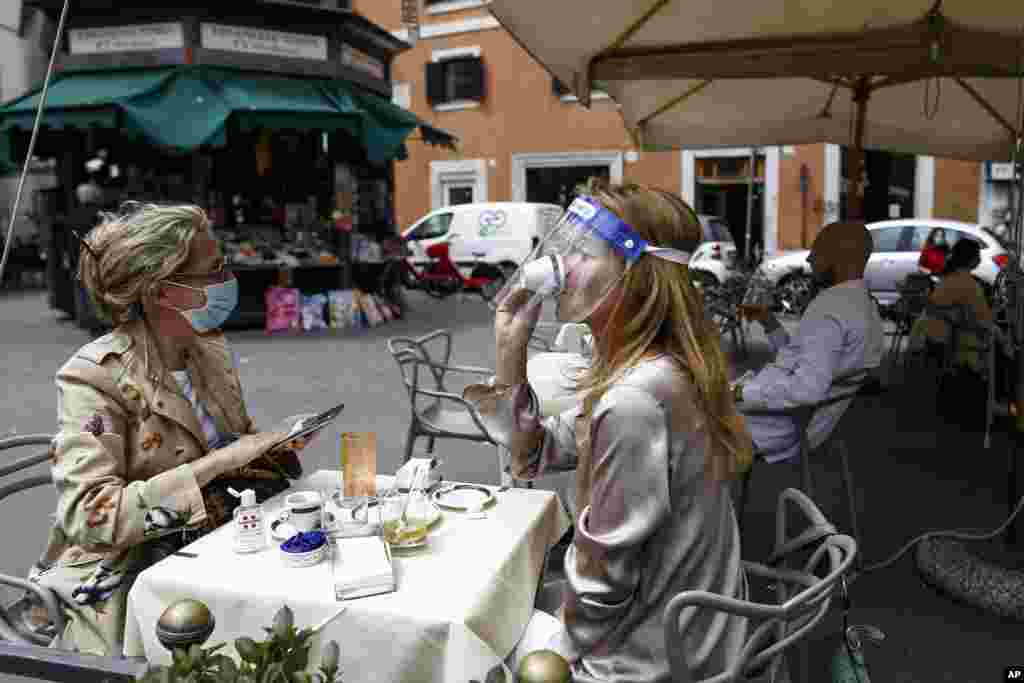 A woman sips her coffee at a cafe in Rome, Italy. Italy is slowly lifting restrictions after a two-month coronavirus lockdown.