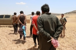 FILE - Men claimed by Syrian Democratic Forces members to be Islamic State fighters are taken prisoner after SDF advanced in Manbij, Aleppo governorate, Syria, May 31, 2016.
