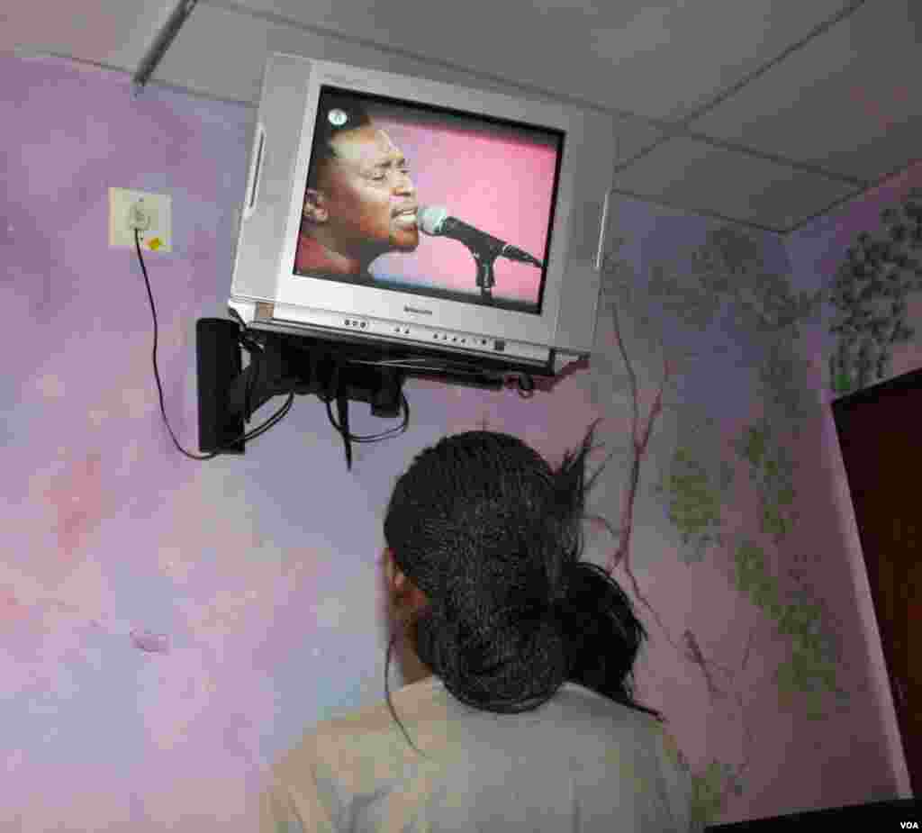 In a pediatric ward, a 16-year-old with HIV and multi-drug resistant tuberculosis who battles to talk and to breathe watches television. She plans to become a doctor who will help others. (Photo by Darren Taylor) 