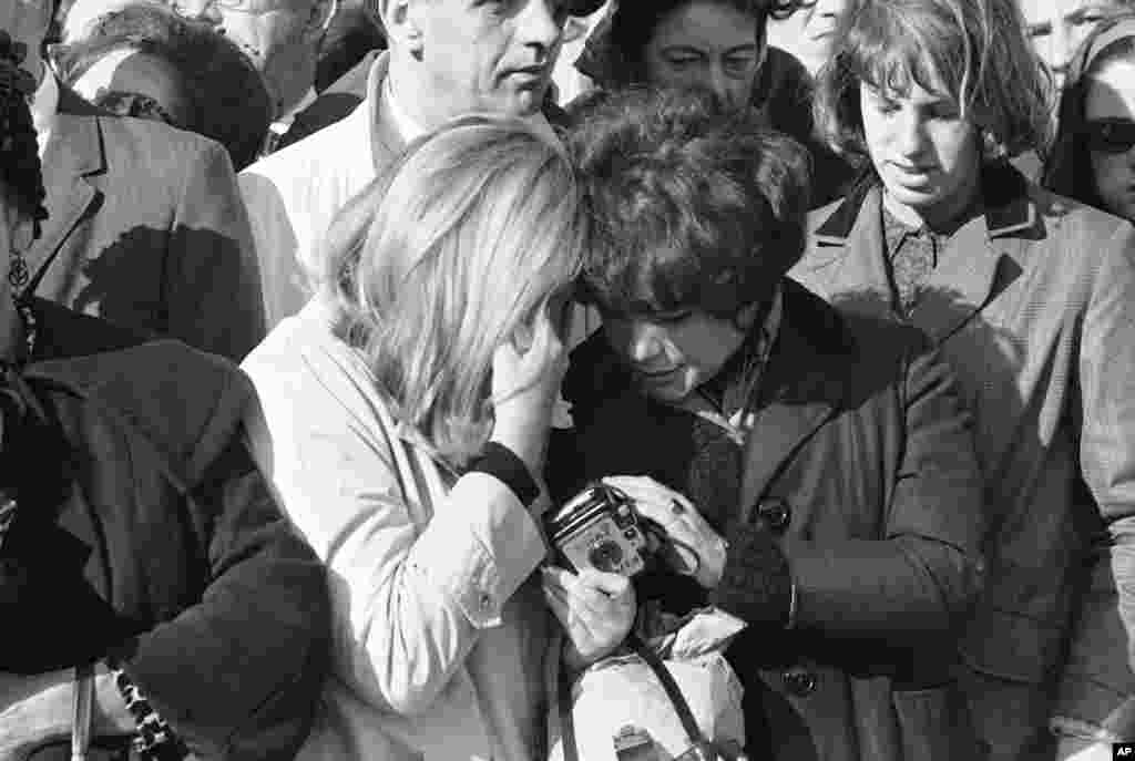 A tearful woman is comforted by a companion as the horse-drawn caisson bearing the body of President John F. Kennedy passes on way to the Capitol, Washington, Nov. 24, 1963.