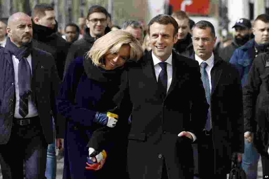 French President Emmanuel Macron and his wife Brigitte Macron walk down the Champs-Elysees avenue after the opening of the Cafe Joyeux coffee shop, in Paris. This chain of coffee shops is staffed by people with Down syndrome, autism and other cognitive disabilities.