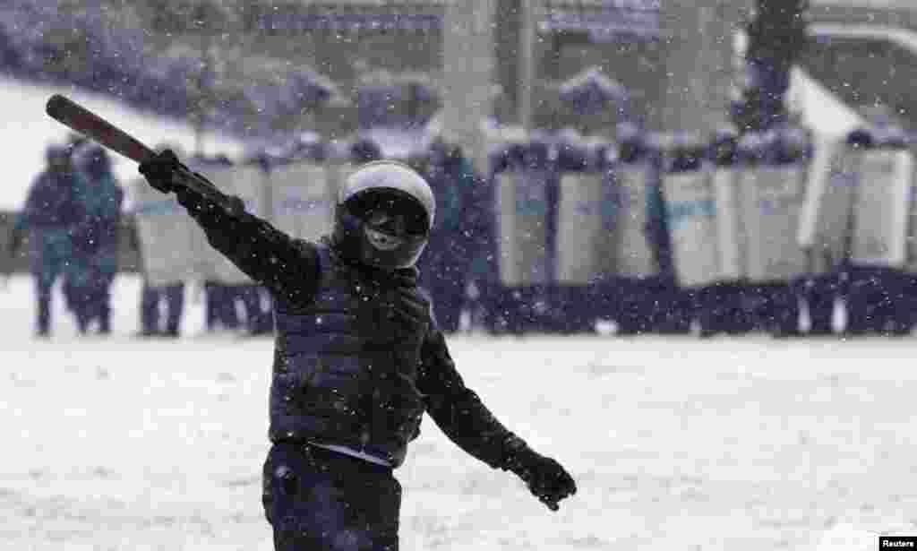 A pro-European protester gestures, with riot police officers seen in the background, during a rally in Kyiv, Jan. 22, 2014.