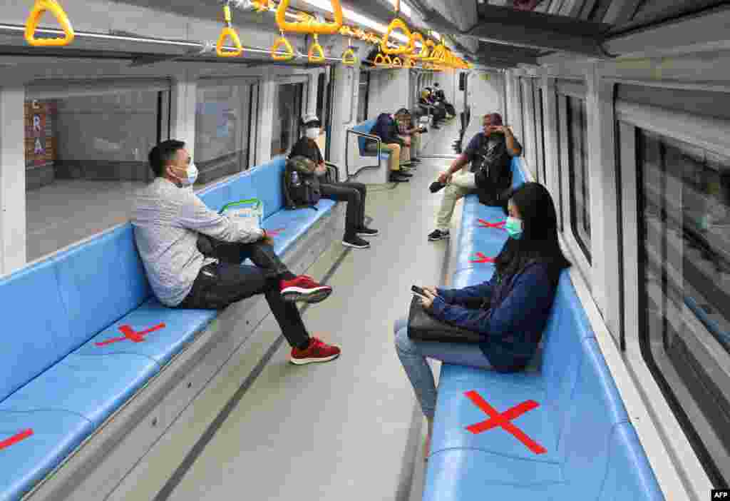 People sit on areas designated by red cross marks to ensure social distancing inside a light rapid transit train in Palembang, South Sumatra, Indonesia.