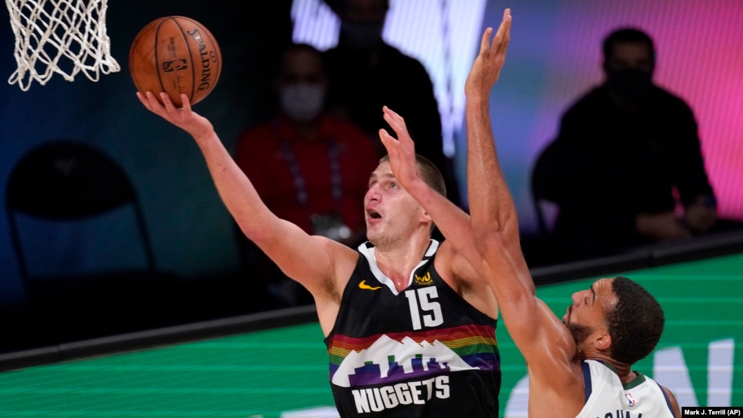 Nikola Jokić postiže poene pored Rudija Gobera, u drugom poluvremenu sedme utakmice prvog kola plej-ofa u Orlandu (Foto: AP/Mark J. Terrill)