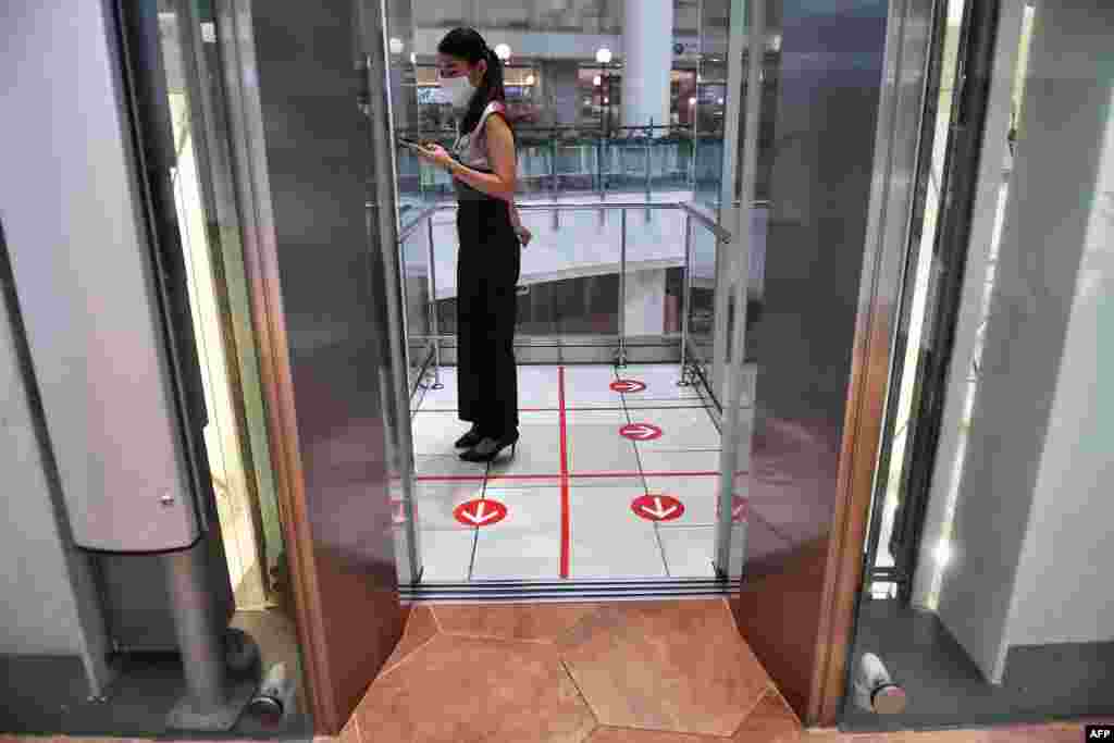 A woman stands in an elevator with markers on the floor for social distancing measures in a shopping mall amid concerns over the spread of the COVID-19 coronavirus in Bangkok, Thailand.