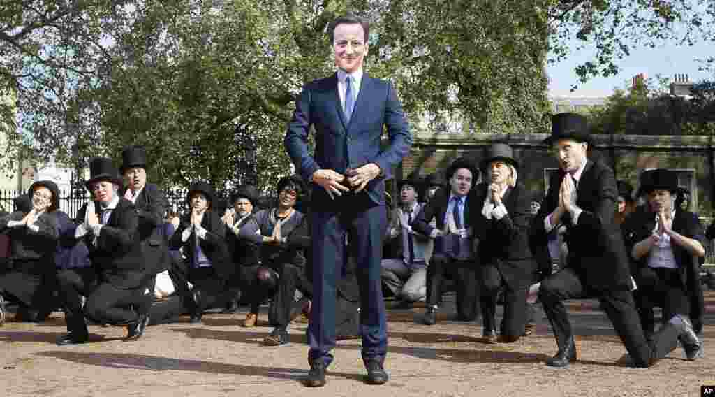 Tarian spontan ‘Artful Tax Dodgers’ termasuk seorang pengunjuk rasa yang mengenakan topeng PM Inggris, David Cameron, bernyanyi dan menari di pintu masuk Lancaster House, dimana pertemuan puncak Anti Korupsi berlangsung di London.