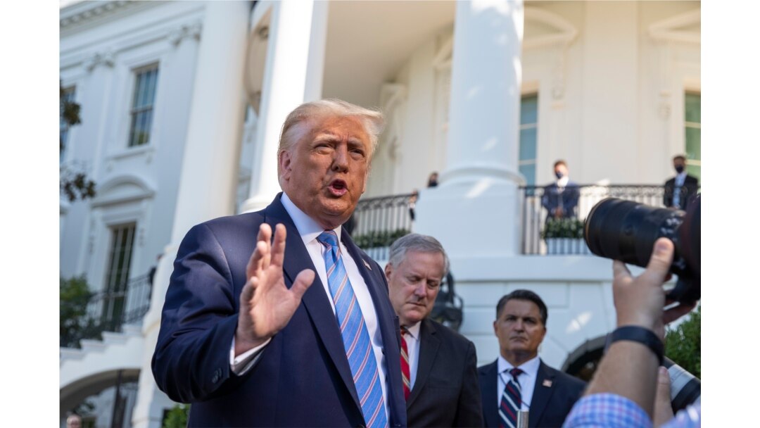 FILE - President Donald Trump, accompanied by White House Chief of Staff Mark Meadows, second from left, speaks with reporters on the South Lawn of the White House, in Washington, July 29, 2020.