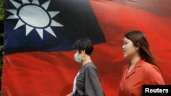 大眾從台北街頭的台灣旗幟旁走過。（2020年8月10日）