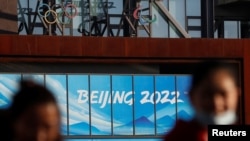 People wearing face masks following the coronavirus disease (COVID-19) outbreak are seen near the office complex of Beijing Organising Committee for the 2022 Olympic and Paralympic Winter Games, a year ahead of the opening of the Games in Beijing, China F