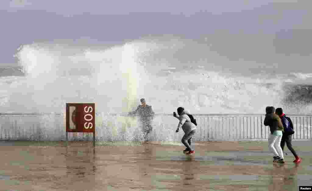 Tourists take a picture with sea waves during the storm "Gloria" on Barceloneta beach in Barcelona, Spain.