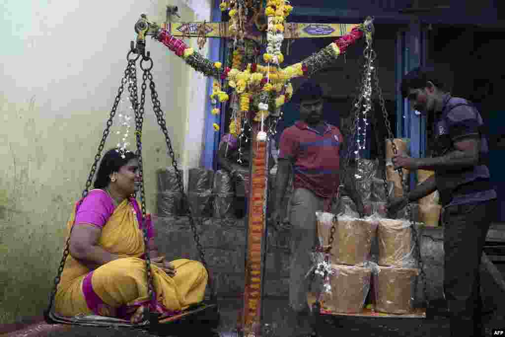A Hindu devotee sits on a scale to buy her weight in jaggery as an offering to goddesses during Sammakka Saralamma Jatara festival, in Hyderabad, India.