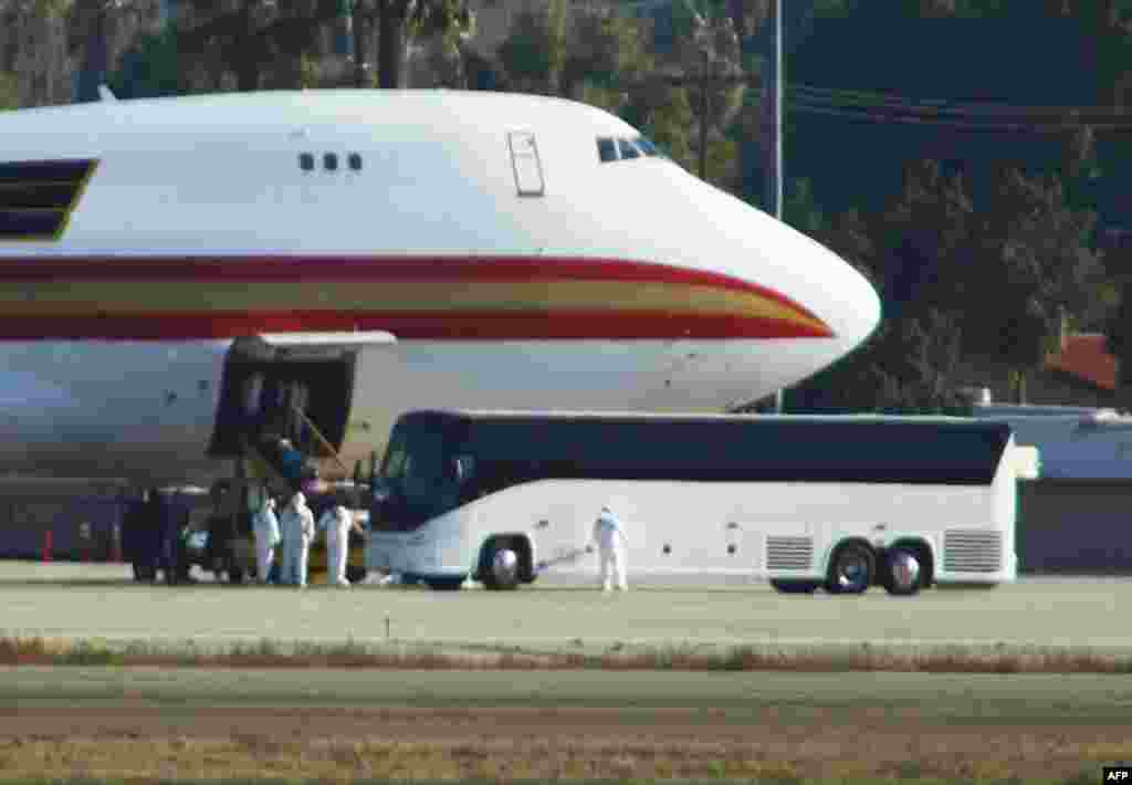 Personnel in biological hazard suits await passengers evacuated from Wuhan, the Chinese city at the heart of a growing outbreak of the deadly 2019 Novel Coronavirus shortly after the plane landed at March Air Reserve Base in Riverside, California. 