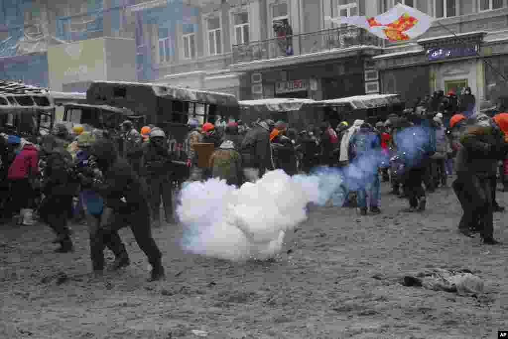 Protesters run away from a stun grenade as they clash with police in central Kyiv, Jan. 22, 2014.