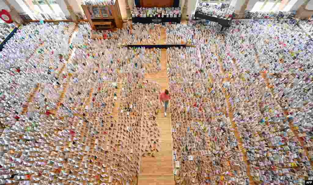 Mandy Alison poses with a selection of over 125,000 birthday cards sent to Captain Tom Moore, for his 100th birthday on April 30, but displayed in the Great Hall of Bedford School, closed-down due to the COVID-19 pandemic, in Bedford, north of London.