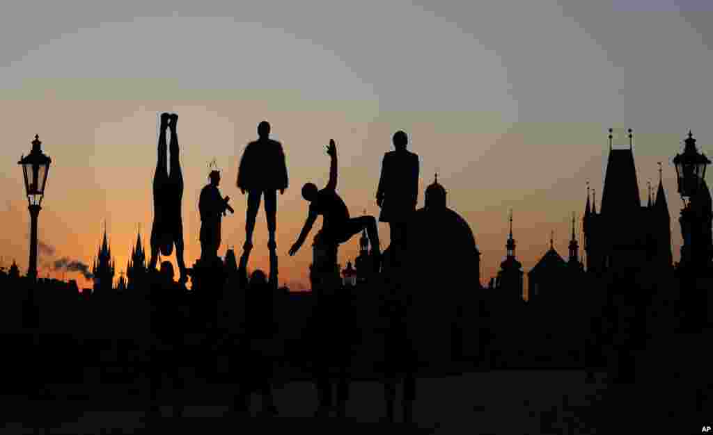 Street artists are silhouetted against the rising sun as they perform on the near empty Charles Bridge in Prague, Czech Republic.